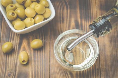 Olive Oil Pouring From Bottle In Bowl And Fresh Olives In Ceramic Plate