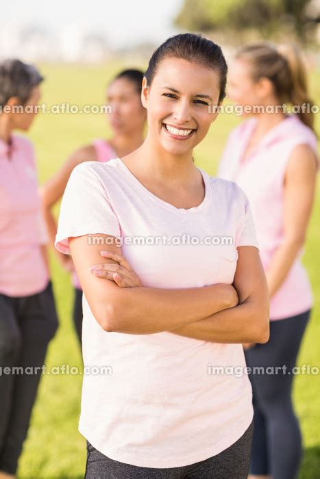 Smiling Brunette Wearing Pink For Breast Cancer In Front Of Friends