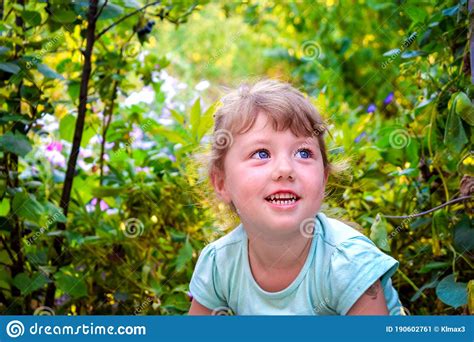 Little Girl Is Sitting In Flower Bush Baby Is Smiling On A Background