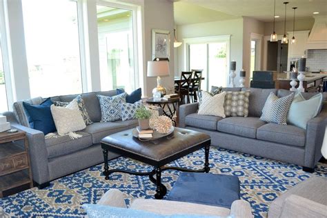 Kate lester interiors nestles a denim ottoman against a dove gray sectional, yielding a space that feels put together and welcoming. Pair of gray sofas with gray leather ottoman and royal blue modern rug. Gorgeous! Fluff Interior ...