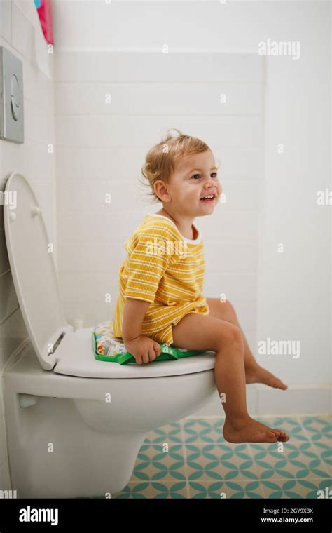 Portrait Of Happy Girl Sitting On Toilet At Home Stock Photo Alamy