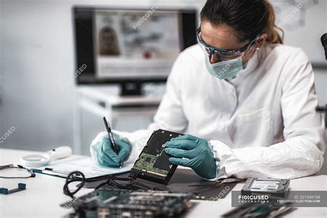 Female Digital Forensic Expert Examining Computer Hard Drive And Taking