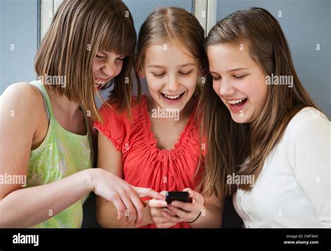 Girls 12 13 Laughing While Looking At Cell Phone Stock Photo Alamy