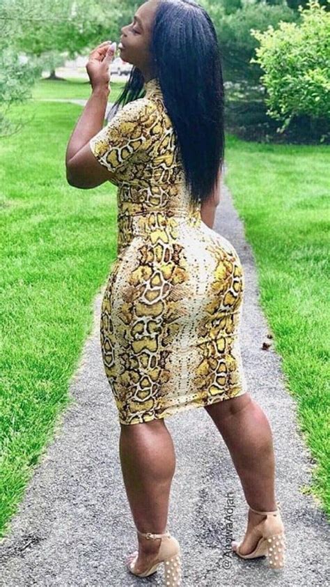 A Woman In A Yellow Snake Print Dress Is Standing On A Path With Her