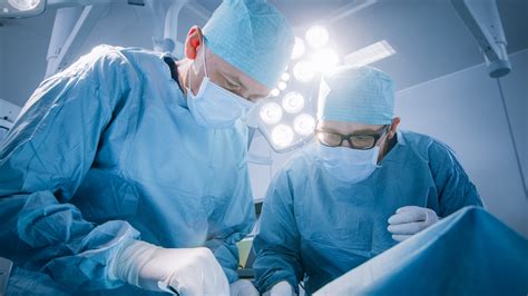 Low Angle Shot In Operating Room Of Two Surgeons During The Surgery Procedure Bending Over