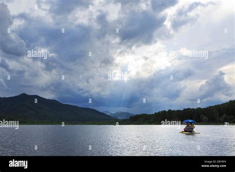 Sunrays Breaking Through Storm Clouds Over Mountain Lake Stock Photo