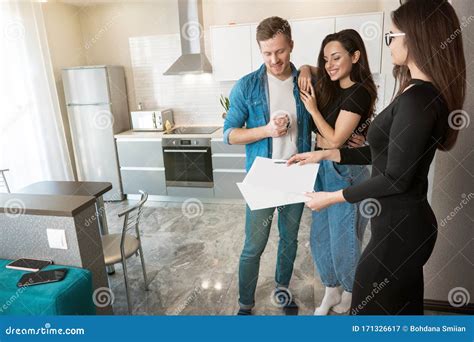 Attractive Woman Realtor Property Manager Showing Plannings Of New Apartment On Sale To Young