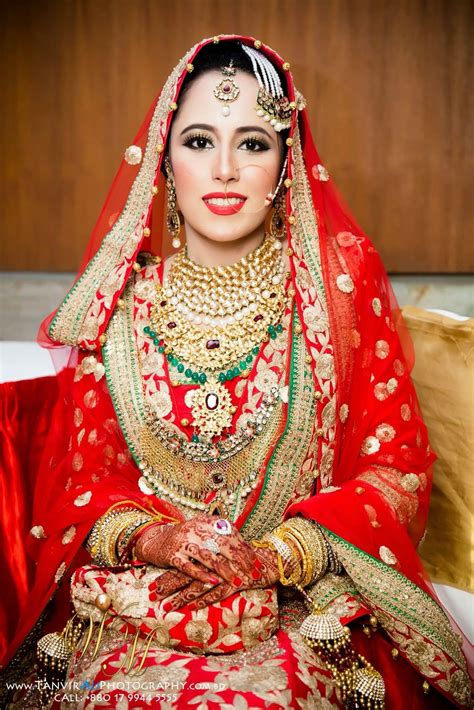 A Woman In Red And Gold Bridal Outfit Sitting On A Couch With Her Hands