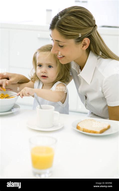 Mother And Daughter Sitting At Table Eating Breakfast Stock Photo Alamy