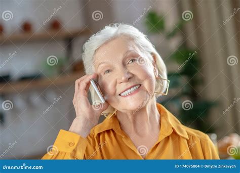 Cheerful Elderly Woman Talking On The Phone With Her Friend Stock Photo