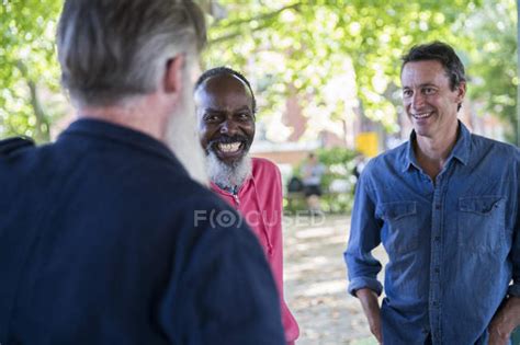 Three Mature Men Talking Outdoors — Male Smiling Stock Photo