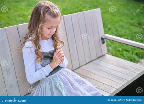 Portrait Of Pretty Child Girl Sitting On Park Bench Outdoors Stock