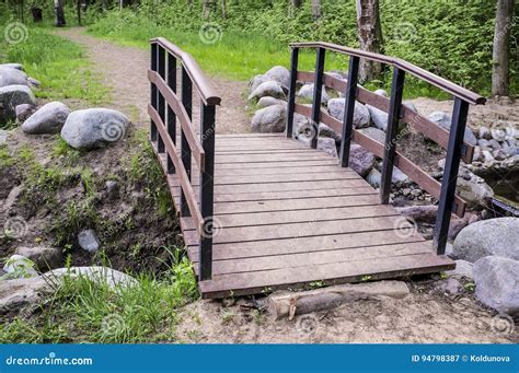 Trail Leads To A Small Wooden Bridge Over The Creek Shore Is Lin Stock