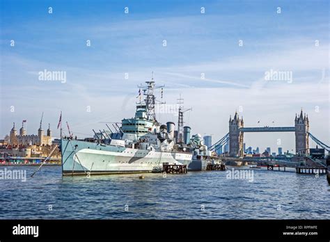 Hms Belfast Moored On The River Thames In Front Of Tower Bridge And The