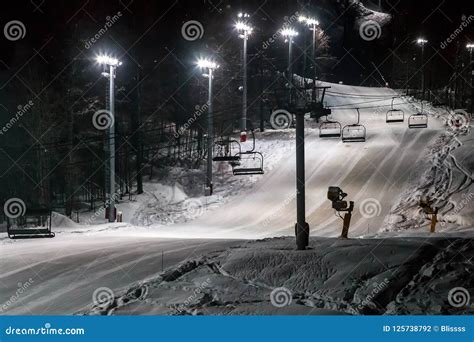 Scenic Night View Of Illuminated Snowy Ski Track With Chair Ski Lift