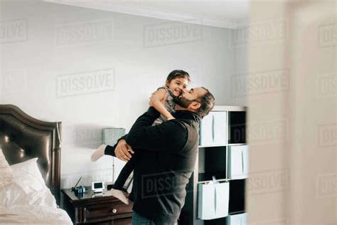 Girl Being Carried And Kissed By Father In Bedroom Stock Photo Dissolve