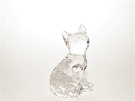 A Glass Cat Figurine Sitting On Top Of A White Table Next To A Wall
