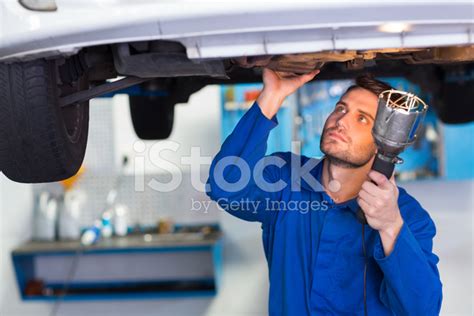 Mechanic Examining Under The Car With Torch Stock Photos
