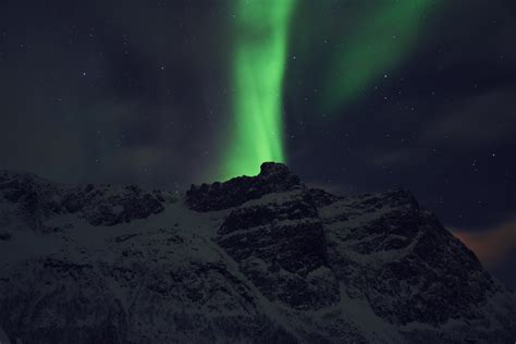 Green Northern Lights Rises Above Snow Covered Mountains In Troms