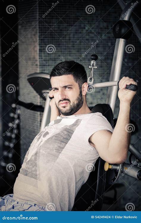 man using pull down machine in gymnasium handsome muscular man exercising on pull down machine