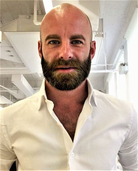 A Man With A Bald Head And Beard Wearing A White Shirt In An Office Setting