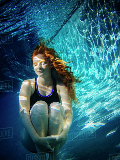 Teenage Girl With Red Hair Swimming Underwater In Pool Stock Photo