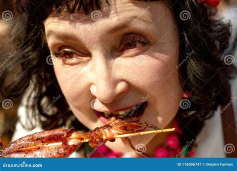 Adult Woman Is Eating Squid With Skewers In The Summer Outdoors Stock