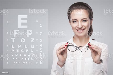 Woman Holding Glasses In Hands With Snellen Test Chart On Background