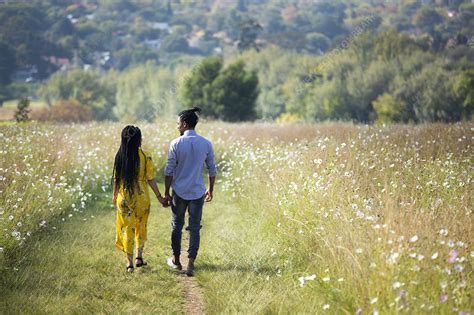 Couple Holding Hands Walking Together In Field Stock Image F033