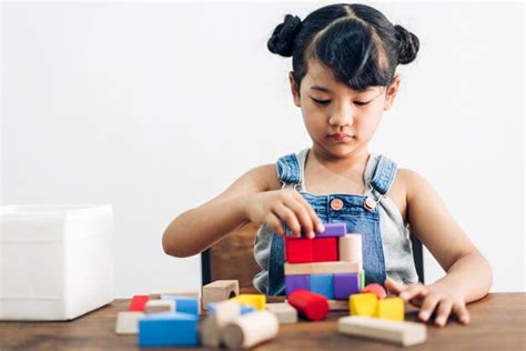 Niña Linda Disfruta Jugando Juguetes De Bloques De Madera En La Mesa En Casa Foto Premium