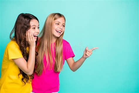 Photo Of Two Nice Cute Cheerful Girls With One Of Them Pointing At Emptiness And Second Being
