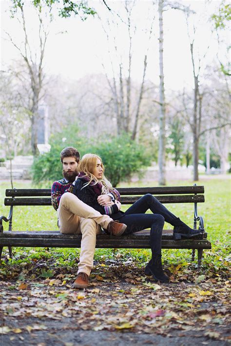 Fashionable Young Couple Sitting On A Bench In The Park By Stocksy