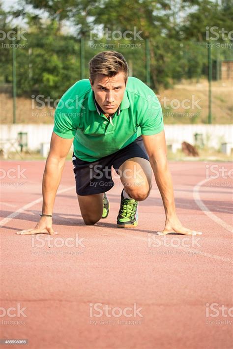 Male Sprinter In Clothes At Start Position On Red Track Stock Photo