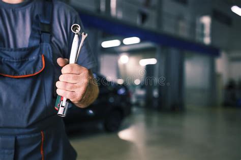 The Hand Of A Car Repairman With Keys And A Special Tool On The