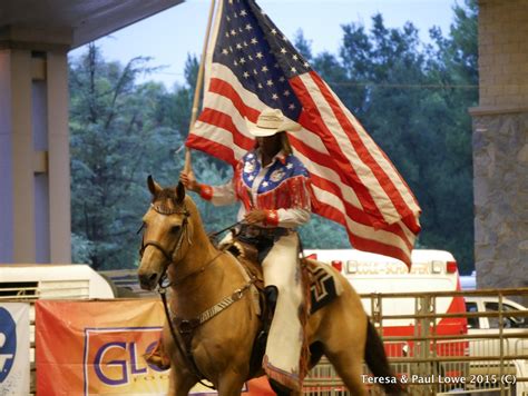 One Of The Cowgirl Riders Carries The United States Flag During The