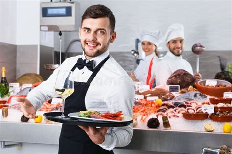 Waiter Holding Tray With Seafood Dishes At Fish Restaurant Against
