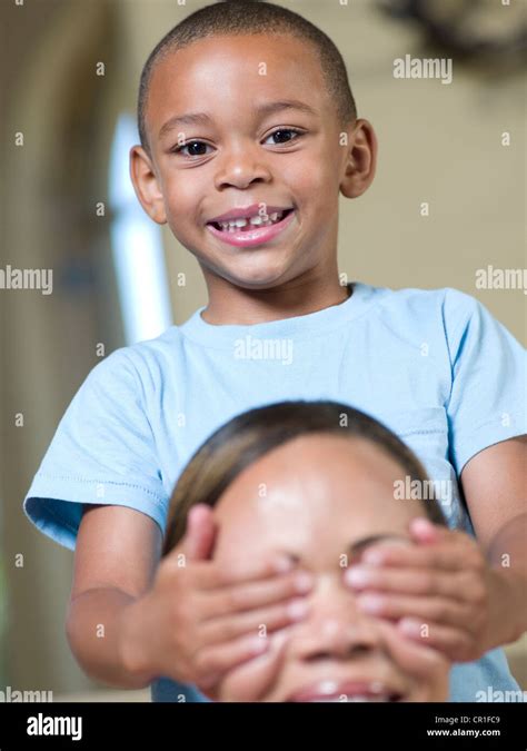 Chico Sonriente Que Cubre Los Ojos De Las Madres Fotografía De Stock Alamy