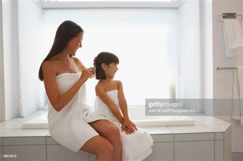 Mother And Daughter Wrapped In Towels Brushing Hair Photo Getty Images