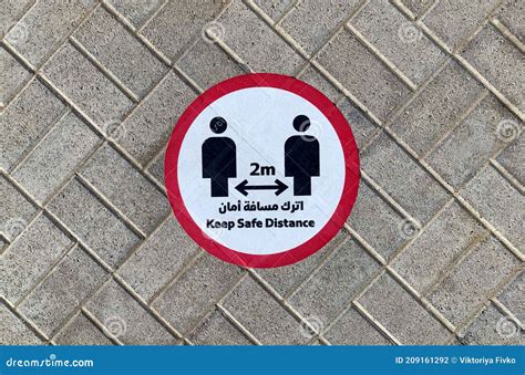 Keep Safe Distance Sticker Sign On A Street Pavement Next To Metro Station In English And