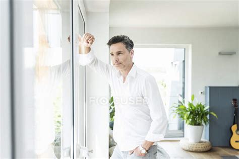 Serene Man Leaning On Window At Home — Indoors Success Stock Photo