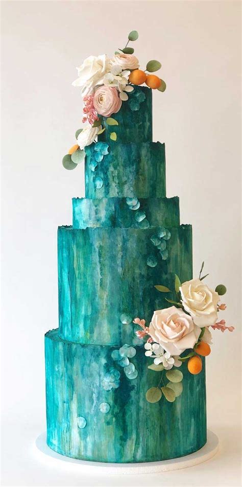A Three Tiered Blue Cake With Flowers On Its Top And Green Icing