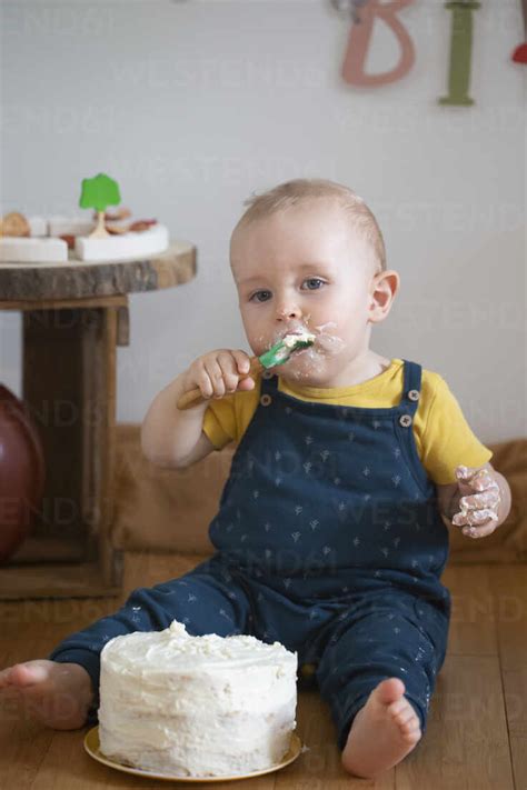 Baby Boy Eating Cake On His First Birthday While Sitting At Home Stock
