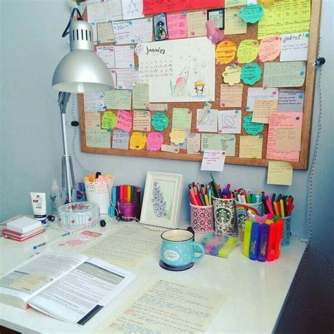 A White Desk Topped With Lots Of Notes And Papers Next To A Wall