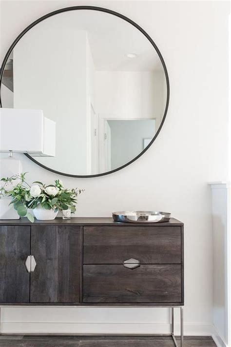 Large Round Black Frame Mirror Mounted Over A Dark Stained Wood Console
