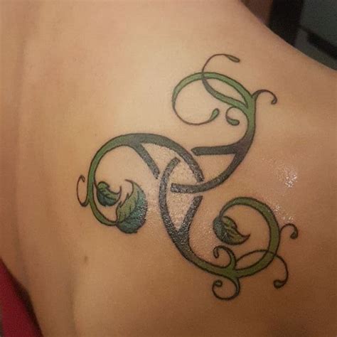 A Tattoo On The Back Of A Womans Shoulder With Vines And Leaves