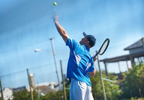 Blasting A Serve A Male Tennis Player Tossing The Ball Up Into The Air