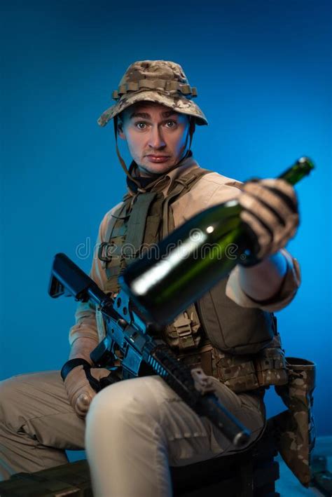 A Drunk Army Soldier In Military Clothes With A Bottle Of Alcohol In
