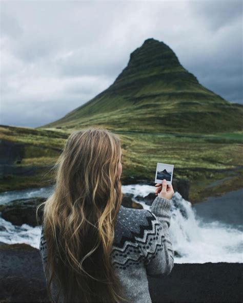 A Woman Is Taking A Photo With Her Cell Phone In Front Of A Waterfall