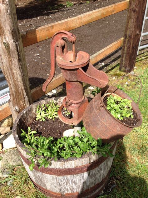Water pours from water pump to wooden basin. Whiskey barrel, old water pump and antique melting pot ...