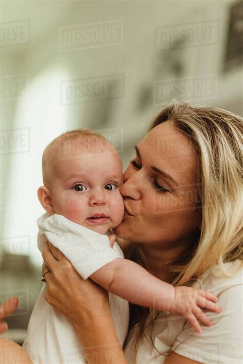 Woman Kissing Baby Daughter On Cheek Stock Photo Dissolve
